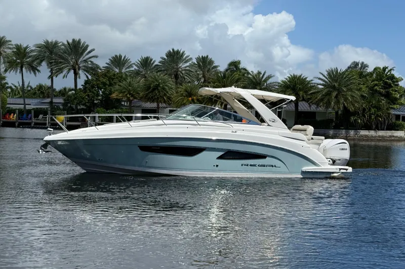 Slide: The Image of 2022 Regal 33 XO boat on calm water with palm trees in the background. - 4