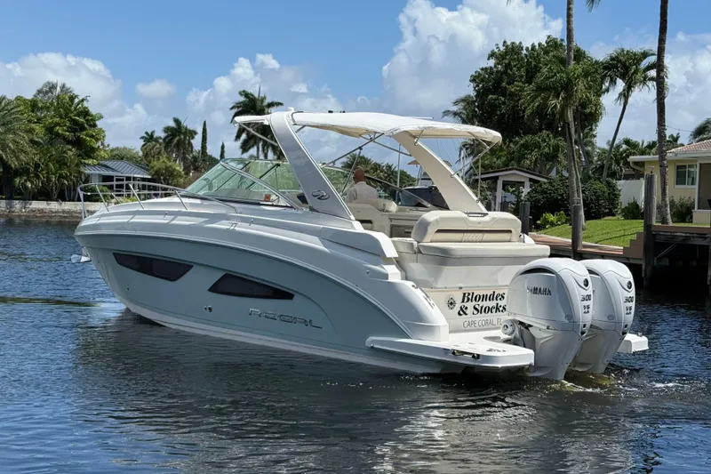 Slide: The Image of 2022 Regal 33 XO boat cruising on a sunny waterway with palm trees in the background. - 5