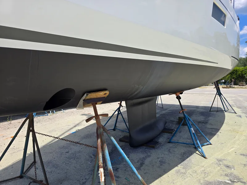 Slide: The Image of The hull of a 2023 Beneteau Oceanis 38.1 is supported on stands on land. - 23
