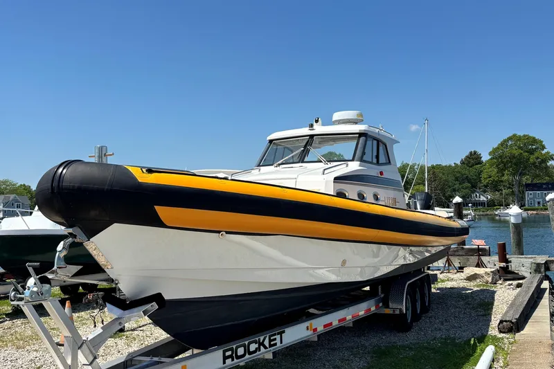 Slide: The Image of 2020 Protector 380 Targa boat on trailer, dockside, under clear blue sky. - 2