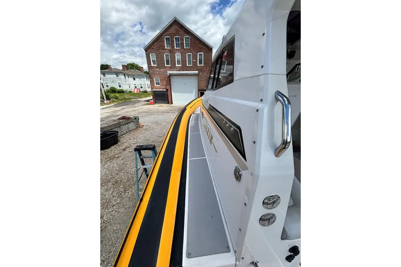 Slide: The Image of 2020 Protector 380 Targa boat docked near a brick building under a cloudy sky. - 4