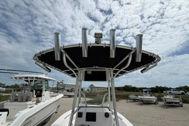 Slide: The Image of 2019 Sea Born LX21 Center Console boat with T-top and rod holders under a cloudy sky. - 19