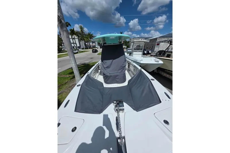 Slide: The Image of 2023 Twin Vee 240 GFX CC boat with protective covers, parked under a clear blue sky. - 5