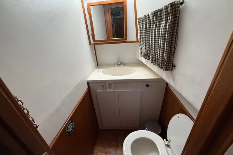 Slide: The Image of Compact bathroom in a 1995 Harbor Master 52 Wide Body boat, featuring sink and toilet. - 24