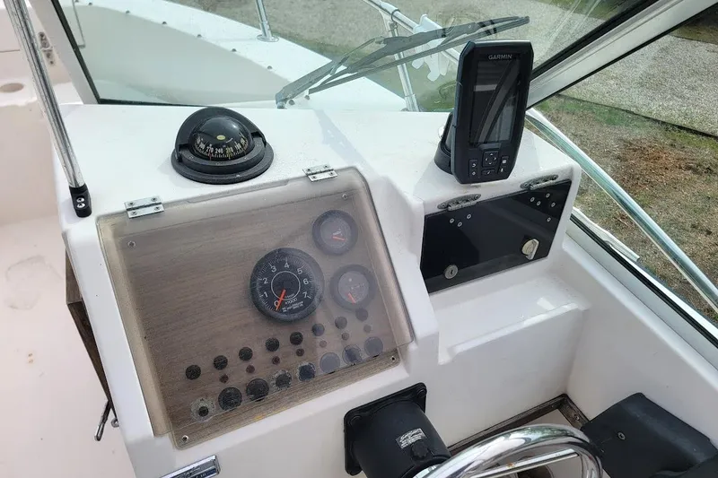 Slide: The Image of 1988 Grady-White Freedom 192 boat dashboard with compass, gauges, and Garmin device. - 10