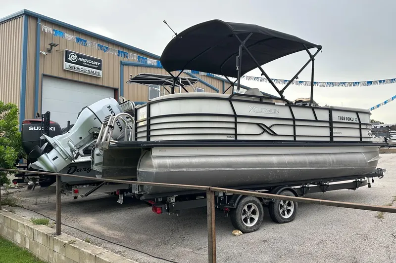 Slide: The Image of 2021 Xcursion 223 RFX pontoon boat on trailer outside service center. - 2