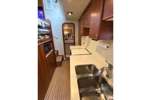 Slide: The Image of Interior of 2006 Endeavour 44 TrawlerCat, featuring a compact kitchen with wooden cabinetry. - 16