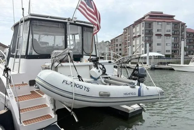 Slide: The Image of 2006 Endeavour 44 TrawlerCat with dinghy, docked near waterfront buildings. - 38