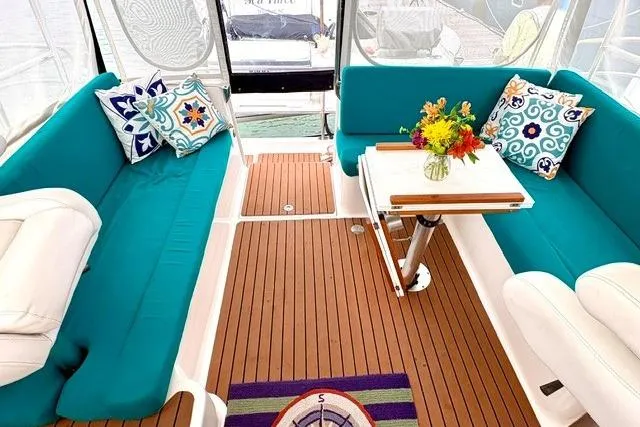 Slide: The Image of Interior of 2006 Endeavour 44 TrawlerCat with teal seating, decorative pillows, and a wooden table. - 4