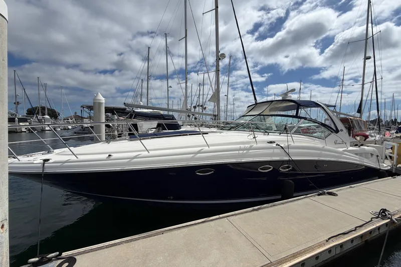 The Image of 2003 Sea Ray 420 Sundancer yacht docked at a marina under a cloudy sky. - 0