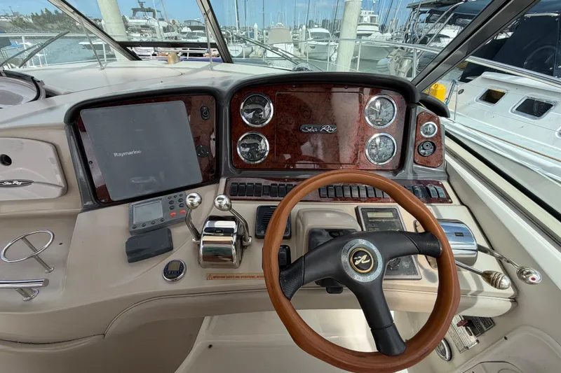 Slide: The Image of 2003 Sea Ray 420 Sundancer helm with wood steering wheel and navigation instruments. - 11