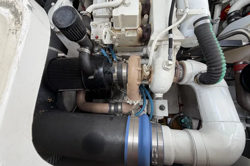 Slide: The Image of Engine compartment of a 2003 Sea Ray 420 Sundancer, showcasing mechanical components and hoses. - 54