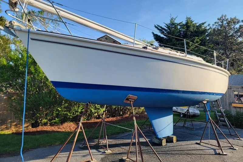 The Image of 1986 Pearson 28 sailboat on stands, blue hull, outdoor setting. - 0