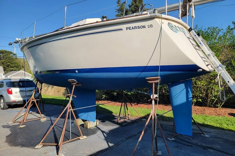 Slide: The Image of 1986 Pearson 28 sailboat on stands, blue hull, parked outdoors. - 1