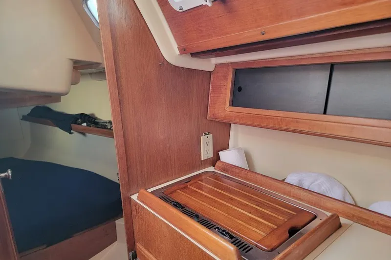Slide: The Image of Interior of a 1986 Pearson 28 sailboat, featuring wooden cabinetry and a cozy sleeping area. - 15