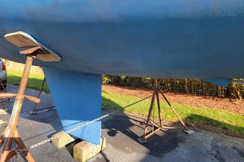 Slide: The Image of 1986 Pearson 28 sailboat hull on stands, blue paint, outdoor setting. - 4