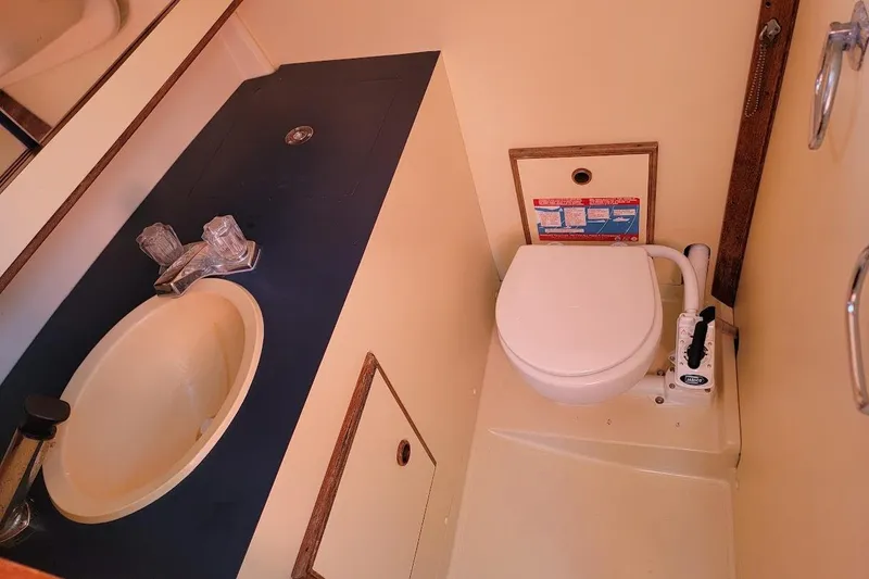 Slide: The Image of Compact marine bathroom in a 1986 Pearson 28 sailboat, featuring a sink and manual toilet. - 8