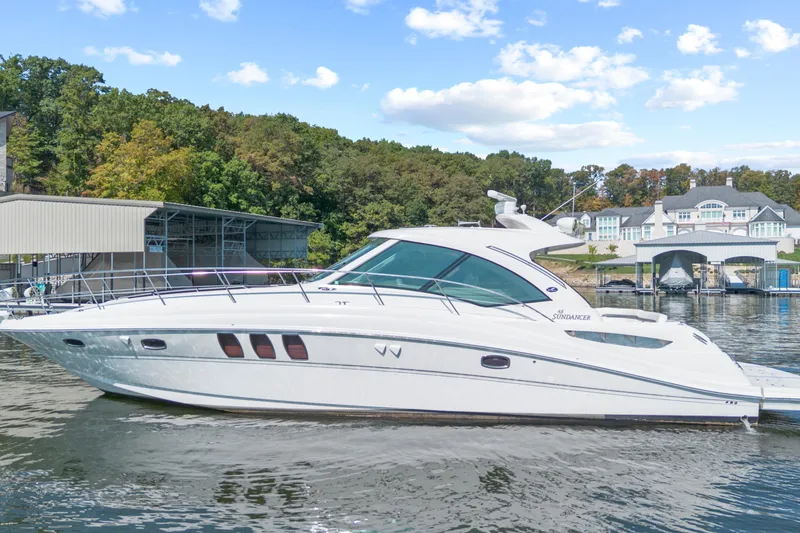 The Image of 2006 Sea Ray 48 Sundancer yacht cruising on a scenic lake with lush greenery. - 0