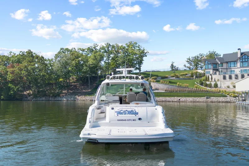 Slide: The Image of 2006 Sea Ray 48 Sundancer yacht on a serene lake near luxury homes. - 1