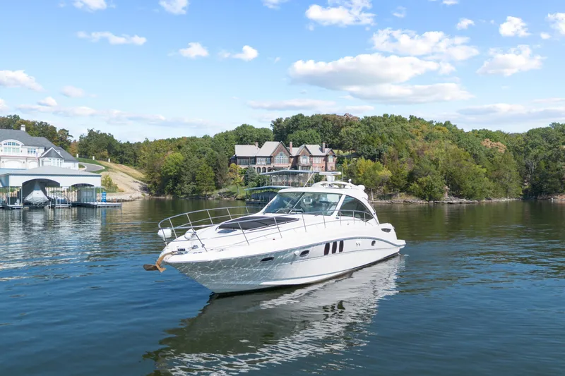 Slide: The Image of 2006 Sea Ray 48 Sundancer yacht cruising on a scenic lake with lush greenery. - 5