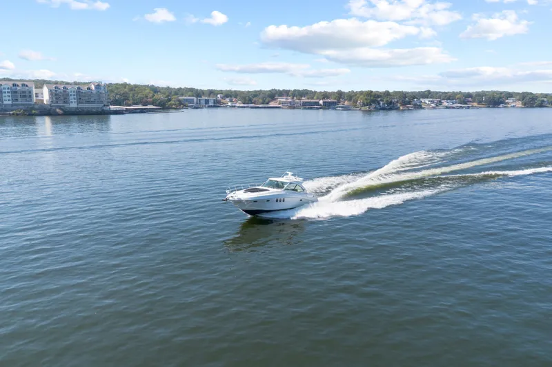 Slide: The Image of 2006 Sea Ray 48 Sundancer cruising on a serene lake under a clear blue sky. - 7
