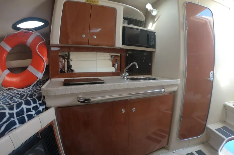 Slide: The Image of 2005 Regal Commodore 2860 boat interior with kitchenette, life preserver, and wooden cabinetry. - 11