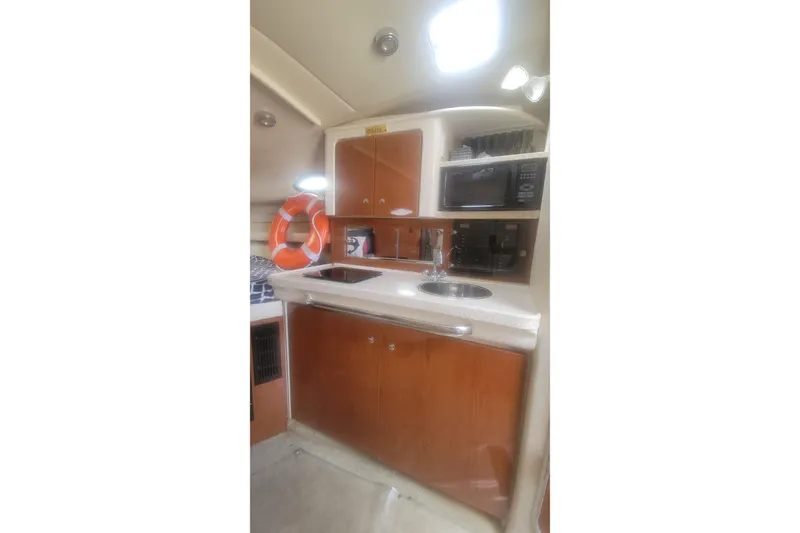Slide: The Image of 2005 Regal Commodore 2860 boat kitchen with wooden cabinets, sink, and microwave. - 9