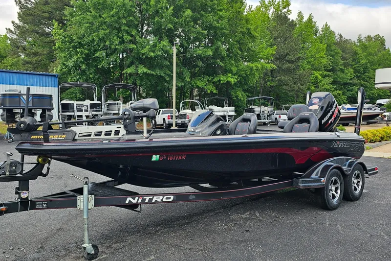 The Image of 2017 Nitro Z20 Pro bass boat on trailer, parked outdoors near trees and other boats. - 4