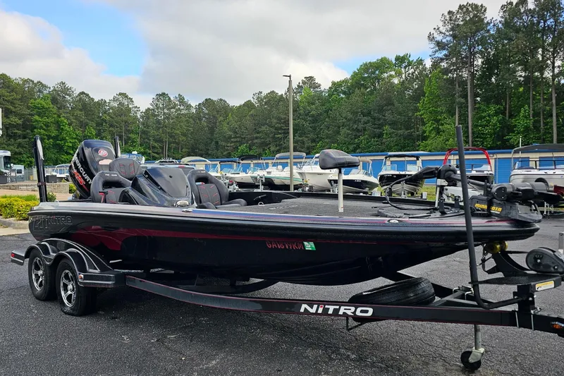 Slide: The Image of 2017 Nitro Z20 Pro bass boat on trailer, parked in marina with trees in background. - 7