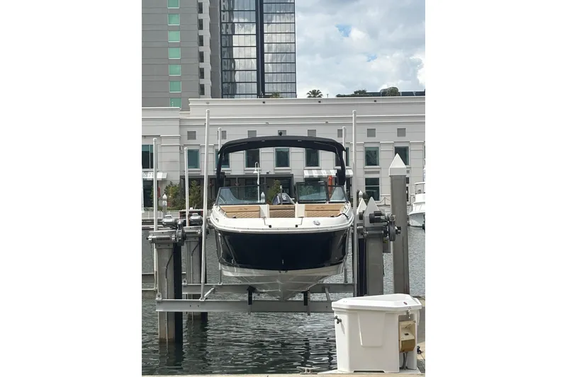 Slide: The Image of 2019 Sea Ray SDX 270 Outboard boat docked at marina with modern buildings. - 1