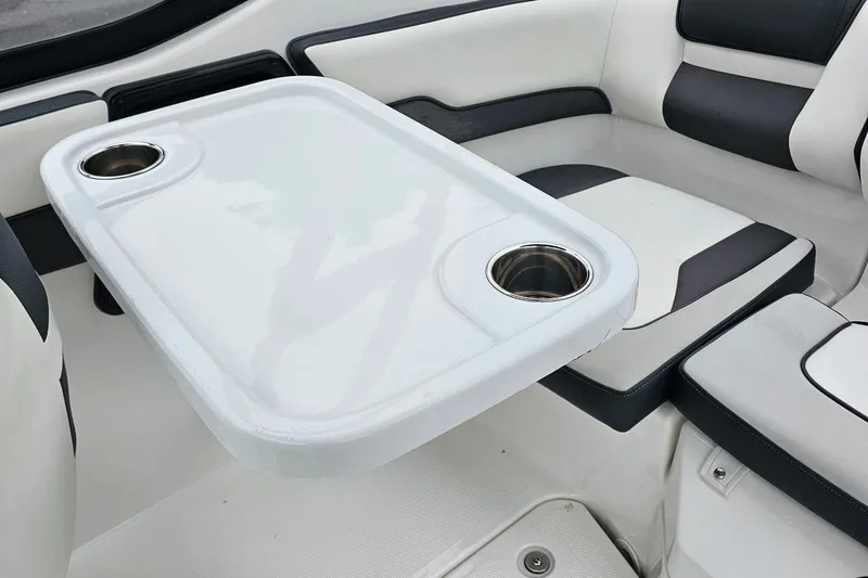 Slide: The Image of 2019 Yamaha AR195 boat interior with white seating and table featuring cup holders. - 18