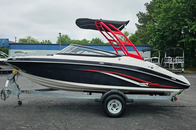 Slide: The Image of 2019 Yamaha Boats AR195 on trailer, black and white design with red accents, parked outdoors. - 32