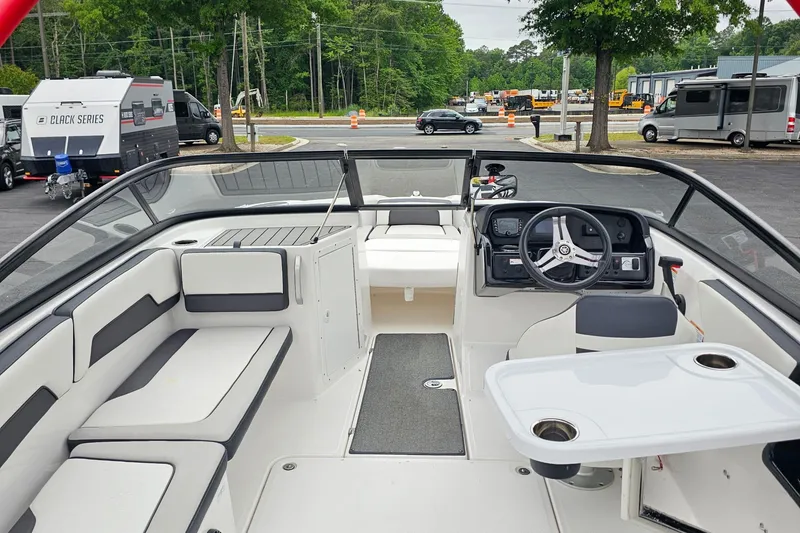 Slide: The Image of 2019 Yamaha Boats AR195 interior with seating, steering wheel, and table in a parking lot setting. - 6