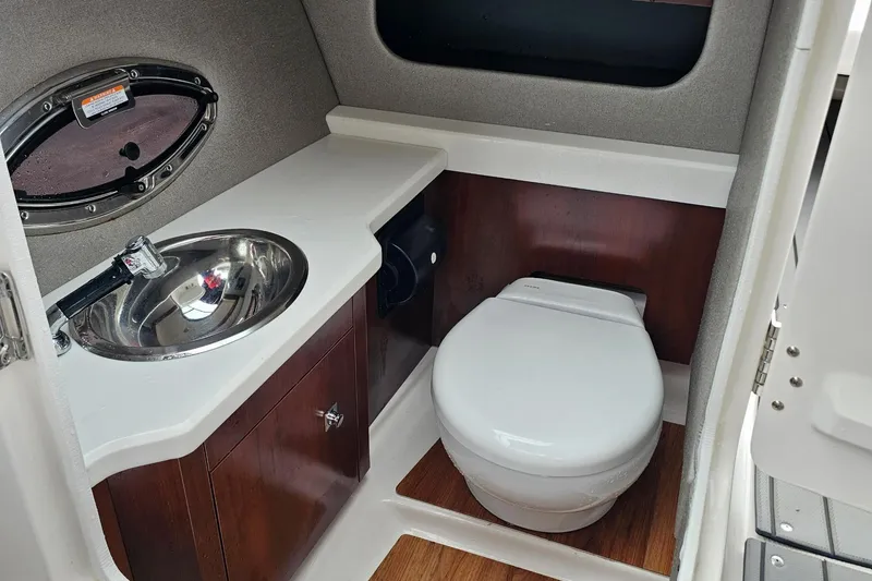Slide: The Image of 2021 Chaparral 307 SSX boat bathroom with sink and toilet, featuring modern design. - 22