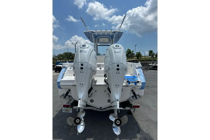 Slide: The Image of 2025 Robalo R270 Center Console boat with dual outboard engines, parked under a sunny sky. - 14