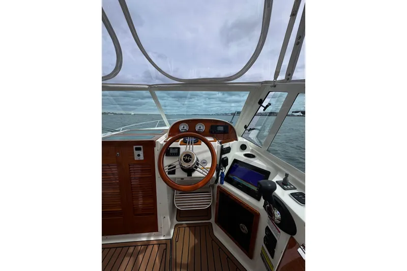 Slide: The Image of Cockpit view of 2020 Hunt Yachts Harrier 26, featuring wooden steering wheel and navigation equipment. - 23