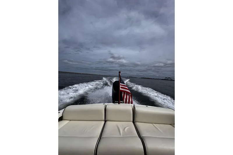 Slide: The Image of 2020 Hunt Yachts Harrier 26 cruising with American flag, leaving a wake under cloudy skies. - 28
