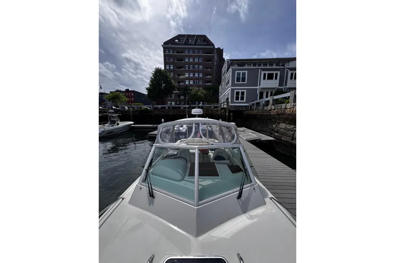 Slide: The Image of 2020 Hunt Yachts Harrier 26 docked near waterfront buildings under a cloudy sky. - 31
