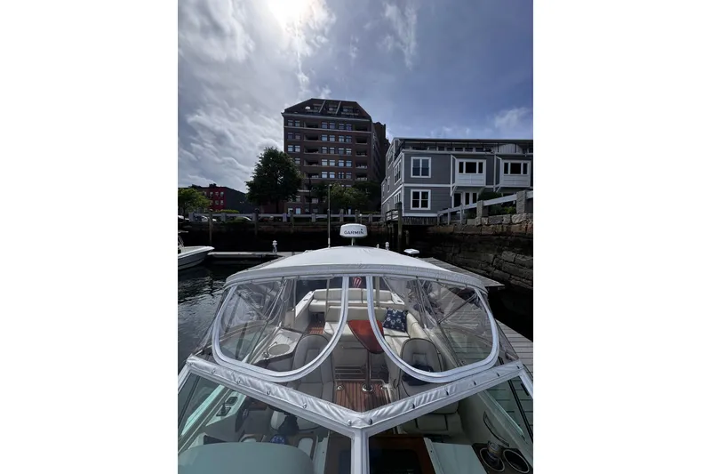 Slide: The Image of 2020 Hunt Yachts Harrier 26 docked near waterfront buildings under a cloudy sky. - 32