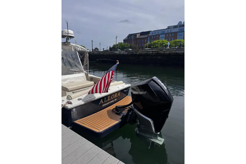 Slide: The Image of 2020 Hunt Yachts Harrier 26 docked, displaying American flag and Mercury outboard motor. - 33