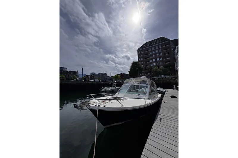 Slide: The Image of 2020 Hunt Yachts Harrier 26 docked under a cloudy sky with sun overhead. - 37