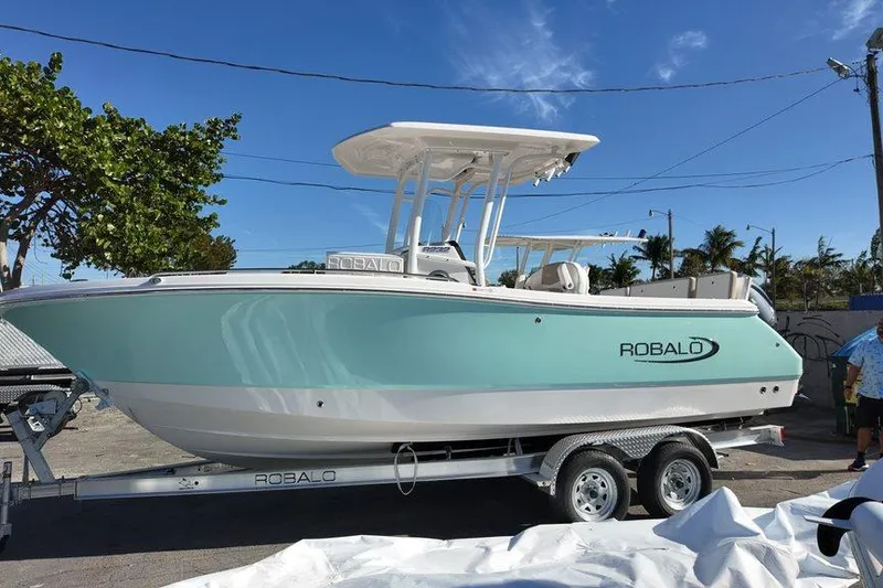 Slide: The Image of 2025 Robalo R232 Explorer boat on trailer, parked outdoors under clear blue sky. - 9