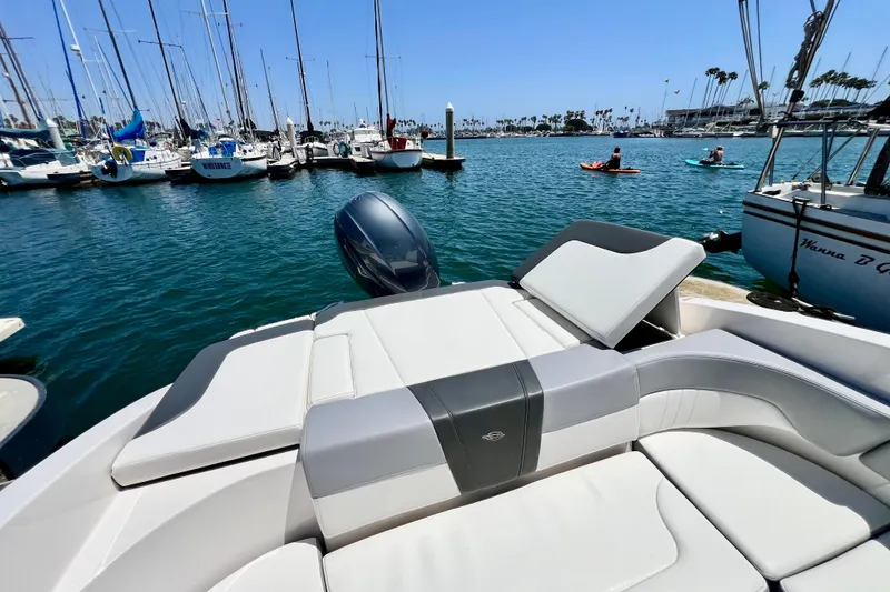 Slide: The Image of 2022 Chaparral 230 SSi boat with luxurious seating, docked in a vibrant marina. - 16