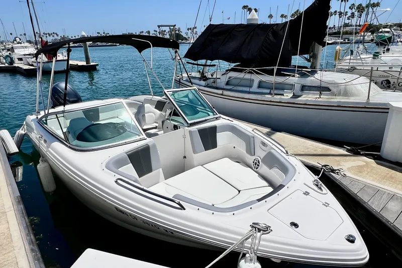 Slide: The Image of 2022 Chaparral 230 SSi boat docked at marina, featuring sleek design and spacious seating. - 2