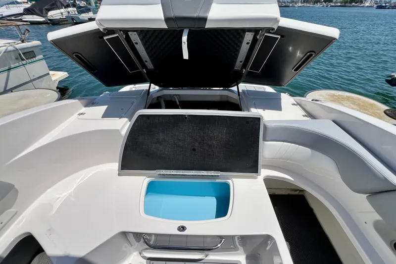 Slide: The Image of 2022 Chaparral 230 SSi boat interior with open storage compartments, docked by the water. - 21