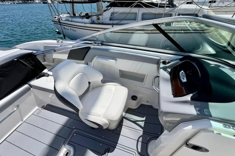 Slide: The Image of 2022 Chaparral 230 SSi boat interior with white seating and dashboard, docked by water. - 33