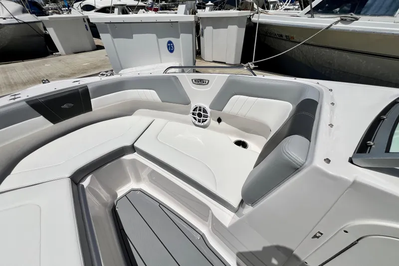 Slide: The Image of 2022 Chaparral 230 SSi boat interior with white and gray seating at a marina. - 40