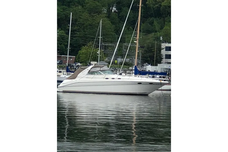 The Image of 1997 Sea Ray Sundancer 370 yacht docked in a marina, surrounded by trees. - 0