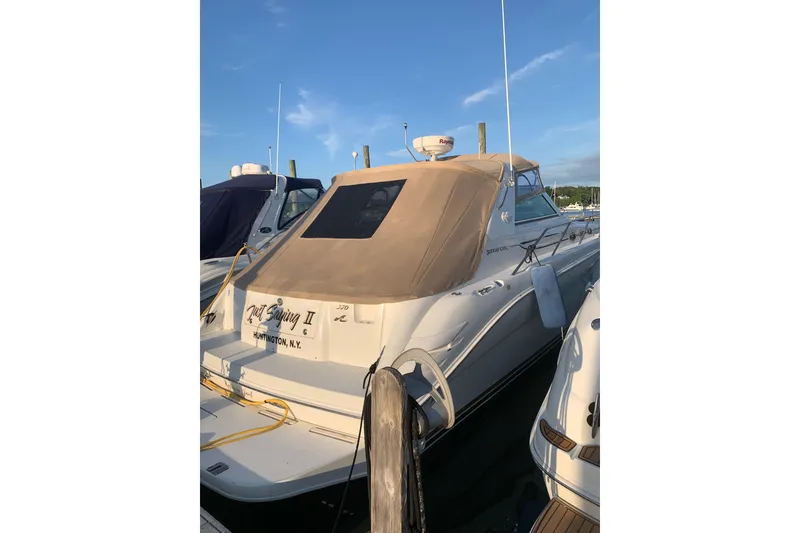 Slide: The Image of 1997 Sea Ray Sundancer 370 docked, featuring beige canopy and sleek design. - 4