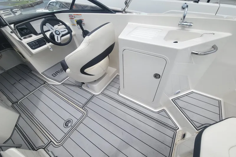 Slide: The Image of 2023 Bayliner DX 2200 boat interior with steering wheel and sink area. - 5